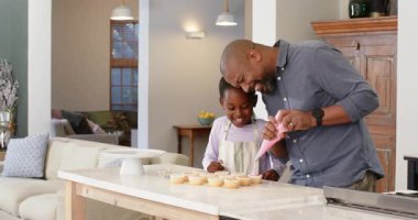 Afro-Amerikalı baba, mutfak adasında pipo torbası topluyor kızına krema çevirmeyi öğretiyor. Aile bağları, akıl hocalığı, sıcaklık, yaratıcılık, işçilik, ev yemekleri, eğitim aktiviteleri.