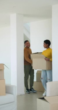Dikey video: Afro-Amerikalı çift evlerinde taşınan kutuları boşaltıyor ve yeşil kazaklarını gösteriyor. İkamet, taşınma, işbirliği, minimalizm, modern tasarım, yaşam tarzı, dikey video