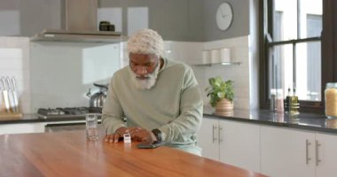 Afrika kökenli Amerikalı kıdemli bir adam, ev mutfağındaki sensörlerin üzerine parmak basıyor. Sağlık verileri için telefon taraması yapıyor. Sensör, teknoloji, sağlık, modern, dijital, sağlık, elektronik