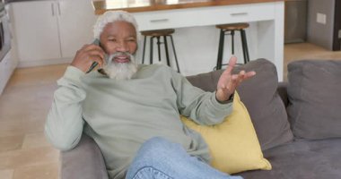 Afrikalı Amerikalı son sınıf öğrencisi telefon alıyor, gülüyor, koltukta düşüncelerini paylaşmak için yer değiştiriyor. Portre, son sınıf, rahatlama, iletişim, ev, samimi, yaşam tarzı