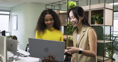 Ofisteki dizüstü bilgisayardan yapılan jest rehberliği ve daktilo raporlarını takip eden çeşitli bayan meslektaşlar. İşbirliği, takım çalışması, profesyonel, modern, üretkenlik, iletişim, yenilik