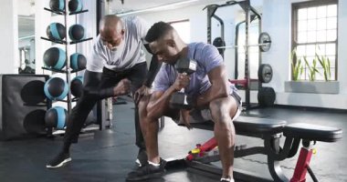 Antrenörden sonra Afrikalı Amerikalı erkek stajyer beden eğitiminde güç toplamak için halterli kıvrımlar yapıyor. Fitness, kuvvet, kişisel eğitim, spor, egzersiz, kas geliştirme, motivasyon