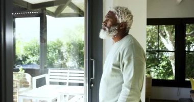 Güneş ışığı, Afrika kökenli Amerikalı son sınıf öğrencisini cam kapı tarama bankında kaşlarını çatarak, kopya uzayı çiziyor. Düşünce, sükunet, doğal ışık, yerli, modern, rahat, içgözlem