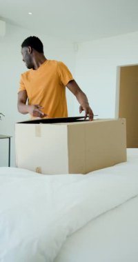 Dikey video: Afrikalı Amerikalı baba ve oğul yatak odasındaki kutuları açıyorlar. Aile, bağ, yer değiştirme, organizasyon, yerli, yaşam tarzı, dikey video