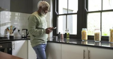 Ping, kıdemli Afro-Amerikalı bir adamın mutfakta telefon kaydırarak tablet çalmasına ve suratının gülmesine neden oluyor. Otomasyon, teknoloji, eğlence, modernlik, rahatlama, evcil, yaşam tarzı