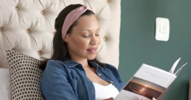 Anne ve küçük kızı yatağa yerleşiyor kitap okuyor uyuyan bebeğe bakıyor, fotokopi çekiyor. Aile, bakım, samimiyet, yakınlık, şefkat, sükunet, evcil