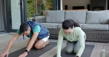 Antrenman çifti, çocuk pozuyla akan selamlaşmaları kapalı verandadaki paspaslarda hafif hamlelere çeviriyor. Fitness, esneme, işbirliği, sağlık, açık hava, aktivite kıyafeti, farkındalık