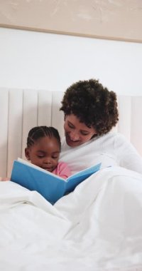 Yatma vakti, Afrikalı Amerikalı anne ve kız birbirlerine bağlanmak için masal kitabı okuyorlar. Konfor, bakım, şefkat, okur yazarlık, aile, şefkat, dikey video