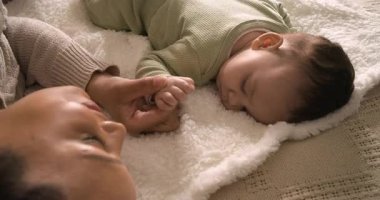 Anne kızının elini tutuyor, seğirmeyi ve okşamayı fark ediyor ve yatak odasındaki battaniyede bebeği sakinleştiriyor. Annelik, bağlılık, rahatlık, şefkat, dinginlik, samimiyet, ilgi.