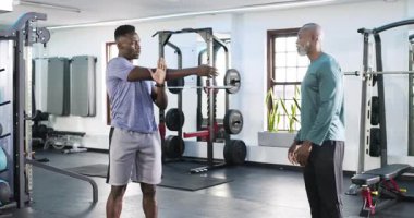 Afrika kökenli Amerikalı erkek antrenör ve müşteri spor salonunda sinyal egzersizi yapmak için ellerini ovuşturduktan sonra çömeliyor. Güç, fitness, antrenman, egzersiz, egzersiz, sağlık, sağlık