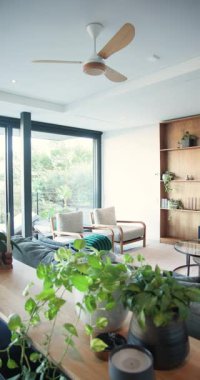 Dikey video: Kamera tavan vantilatöründen aşağı eğiliyor sonra oturma odası dekorunu ortaya çıkarmak için sağa dönüyor. Modern, botanik, minimalist, iç mekan, rahatlama, doğal, dikey video