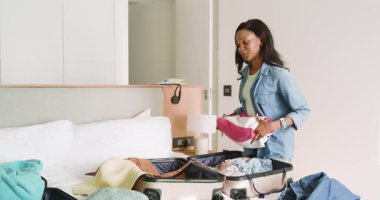 Çizgili havluyu açarak, çift seyahat için açık bavula giysilerini yerleştiriyor. Seyahat, tatil, paketleme, organizasyon, arkadaşlık, boş zaman, yaşam tarzı