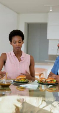 Dikey video: Mutfak tezgahında çeşitli arkadaşları ısıran, sohbet eden ve el kol hareketi yapan hamburgerler. Gündelik yemek, arkadaşlık, iletişim, modern mutfak, samimi, anlamlı jestler, dikey video.