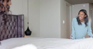 Afrika kökenli Amerikalı arkadaşlar yatak odasında yastık ve çarşaf seriyorlar. Rahat, rahat, rahat, dostluk, iç mekan, minimalizm, ahenk