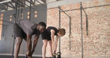 Erkek antrenör formda olduğunu gösterdiğinde, müşteri fitness için jimnastik salonunda kettlebell sallıyor. Güç, egzersiz, eğitim, dayanıklılık, disiplin, hareket, atletizm