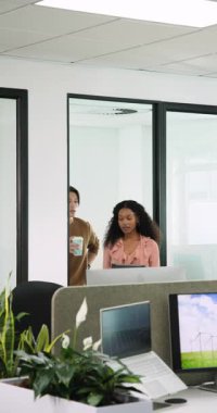 Dikey video: Çeşitli iş arkadaşları çalışma istasyonuna kahve ve tabletle girerek içeriği gözden geçiriyorlar. İşbirliği, teknoloji, profesyonel, iletişim, üretkenlik, modern, dikey video