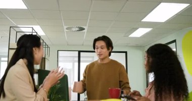 Çeşitli meslektaşlar kahve makinesini mutfakta kullanıyor, bardakları yerleştiriyor ve teneffüste sohbet ediyorlar. İşbirliği, takım çalışması, iletişim, gündelik, profesyonel, modern, sosyal