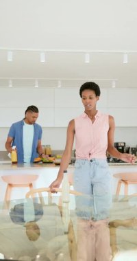 Dikey video: Cam masadaki hamburgerleri düzenledikten sonra yemeğe başlamak için çeşitli ikililer şişe tokuşturuyor. Mutfak, samimiyet, kutlama, modern, yaşam tarzı, yemek, dikey video