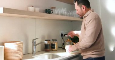 Mutfağa giriliyor, Asyalı erkek kupa seçiyor, adada basından kahve dolduruyor, fotokopi çekiyor. Minimalist, modern, yaşam tarzı, iç mekan, mutfak, içecek, rahatlama