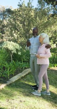 Birçok yaşlı çift bahçede akıllı telefonlarıyla selfie çekerken ağaçtaki kuşun güldüğünü fark ettiler. Son sınıf, boş zaman, açık hava, arkadaşlık, rahatlama, canlılık, dikey video