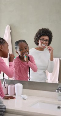 Çeşitli anne ve çocuklar banyo tezgahına tırmanıyor, diş fırçası seçiyor ve dişlerini fırçalıyor. Aile, bakım, bağ, hijyen, sağlık, etkileşim, dikey video