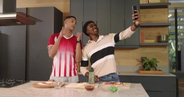 Çeşitli erkek arkadaşlar mutfakta pizza hazırlıyor. Sos üstüne selfie çekiyorlar. Peynir rendeliyorlar. Aşçılık, aşçılık, takım çalışması, kutlama, modern, yaşam tarzı, gündelik