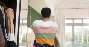 Arkadaş kıyafet seçiminden sonra gardırobu açar, pencerenin yanındaki yatakta kazağını çeker ve açar. Moda, arkadaşlık, yaşam tarzı, iç mekan, gündelik, dekor, iletişim