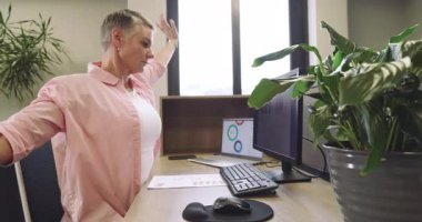 Beyaz kadın, ofis masasındaki gerginliği azaltmak için kollarını açarken monitörlere yazı yazıyor. İşbirliği, üretkenlik, işyeri, modern, takım çalışması, şirket, iletişim