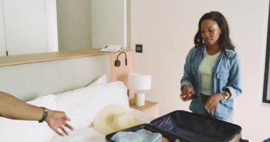 Afro-Amerikalı çift yataklarına bavullarını topluyor, spor ayakkabılarını, gömleklerini ve şapkalarını seyahatten önce değiştiriyorlar. Seyahat, toplanma, macera, yaşam tarzı, seyahat tutkusu, günlük, düzenleme