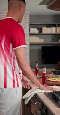 Çeşitli arkadaşlar pizza kesiciyle dilimliyor, mutfak adasında otlar serpiştiriyor, pizza dilimleri tadıyorlar. Günlük, yoldaşlık, aşçılık, modern, sosyal, takım çalışması, dikey video