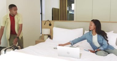 Otel odasına bavullarla giriyorlar, Afro-Amerikan çift dizüstü bilgisayarla bir gezi planlıyorlar. Gezginler, işbirliği, modern, yaşam tarzı, profesyonel, samimi, samimi