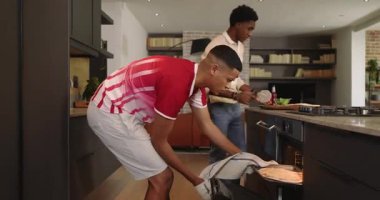 Çeşitli erkek arkadaşlar pizzayı sıcak fırına atıyorlar, dilimliyorlar, içkileri dolduruyorlar ve mutfakta kızartıyorlar. Günlük, yoldaşlık, aşçılık, modern, yaşam tarzı, kutlama, arkadaşlık.