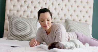 Anne ve yeni doğmuş bebek battaniyeye uzanmış hareketlenirken, battaniyeye dokunurken, bebeği sakinleştirirken, sıcak bir şekilde gülümserken. Annelik, şefkat, rahatlık, dinginlik, samimiyet, şefkat, samimiyet