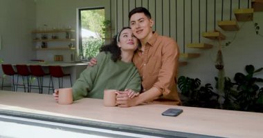 Mutfak tezgahına dayanmış bir çift, kahve fincanlarını tost için kaldırma arzusuyla paylaşıyor. Romantik, samimi, samimi, bağlantı, yaşam tarzı, modern, sıcak