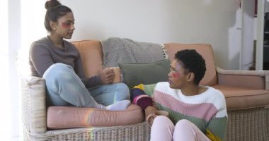 Çeşitli bayan arkadaşların kahve yudumlayarak jel yamalarını evde sohbet olarak göstermesi sohbeti ateşliyor. Sıcaklık, arkadaşlık, rahatlama, sohbet, yaşam tarzı, sıcaklık, konfor.