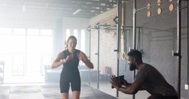 Tablet tıkırdatma antrenörü, kadın sporcunun çömelmesi ve güç için tavan arasındaki kutuya atlaması. Spor, güç, eğitim, performans, atletik, egzersiz, spor