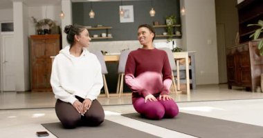 Yoga minderlerinin üzerinde diz çöküp selam veren çeşitli bayan arkadaşlar evde ısınırken omuzlarını esnetiyorlar. Sağlık, farkındalık, bağlantı, egzersiz, uyum, rahatlama, toplum