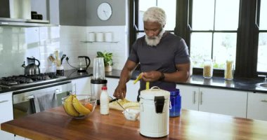 Adam kaseden muz topluyor, kabuğunu soyuyor, kabuğunu çöpe atıyor, mutfakta atıştırmak için muz dilimliyor. Taze üretim, aşçılık, modern, sağlıklı yaşam tarzı, ev yemeği, hazırlık, zindelik