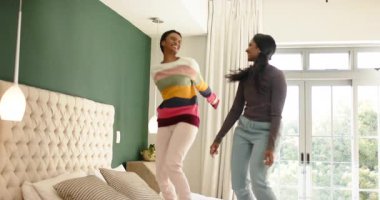 Çeşitli bayan arkadaşlar yatağa atlıyor yatak odasında zıplıyorlar ve akıllı telefon kayıt anını yükseltiyorlar. Arkadaşlık, neşe, rahatlama, neşeli, rahat, yaşam tarzı, samimi