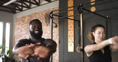 Çeşitli spor partnerleri spor salonunda ısınıyor parmaklarını birbirine geçirip göğüs büküyor. Fitness, takım çalışması, esneklik, şehir, minimalist, güç, sağlık