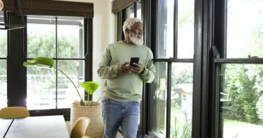 Afro-Amerikalı son sınıf öğrencisi alarm üstüne akıllı telefonu kaydırıyor, gülümseyen hayran bahçesi. Gündelik, rahatlama, açık hava, modern, iç mekan, yeşillik, boş zaman