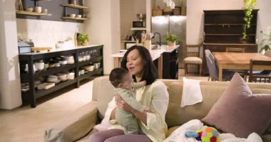 Afrikalı Amerikalı anne beşiği beşikte tutuyor, topu fark ediyor, bebeği oturma odasına bağlamak için zıplıyor. Aile, bakım, sıcaklık, şefkat, bağlantı, ev, rahatlık.