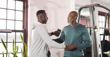 Afrikalı Amerikalı antrenör ve müşteri spor salonuna girip spor çantalarını bırakmayı tartışıyorlar. Fitness, yoldaşlık, eğitim, güç, motivasyon, takım çalışması, sağlık