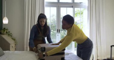 Çeşitli bayan arkadaşlar yatak odasındaki bavullarını fermuarla çekip selfie çekiyorlar. Seyahat, arkadaşlık, günlük, yaşam tarzı, modern, hayat dolu, boş zaman