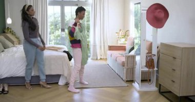 Çeşitli bayan arkadaşlar yeşil elbise teklif ediyorlar. Arkadaşlarına fermuarlı elbiseler giydiriyorlar. Yatak odasında topuklu ayakkabı seçiyorlar. Arkadaşlık, moda, stil, iç mekan, konfor, zarafet, gelişigüzel