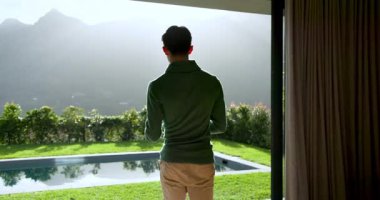 Asyalı bir adam dağ manzaralı terasa çıkarken tableti kapıp bakıyor. Manzara, rahatlama, modern, boş zaman, manzara, teknoloji, sükunet