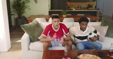 Çeşitli erkek arkadaşlar beyaz kanepeye yaslanıyor, yumruklarını sallıyor, top üstüne top tutuyorlar. Gündelik, dostluk, kutlama, eğlence, modern, sosyal, canlı