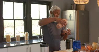 Mutfaktaki bardakları doldurmak için blender sürahisi dolusu pembe, Afro-Amerikalı adam kaldırıyor. Sağlık, beslenme, ev, yaşam tarzı, modern, rahatlama, içecek
