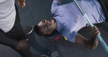 Halter yükledikten sonra, Afrikalı Amerikalı antrenör spor salonunda dayanıklılık için yedek kulübesinde stajyere rehberlik ediyor. Güç, fitness, antrenman, spor, spor, motivasyon, fiziksel