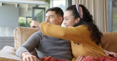 Evdeki çift sürgülü cam kapıyı işaret ediyor, kırmızı atışıyla kanepeye uzanıp sarılıyorlar. Romantik, mahremiyet, bağlantı, uyum, konfor, şefkat, ev